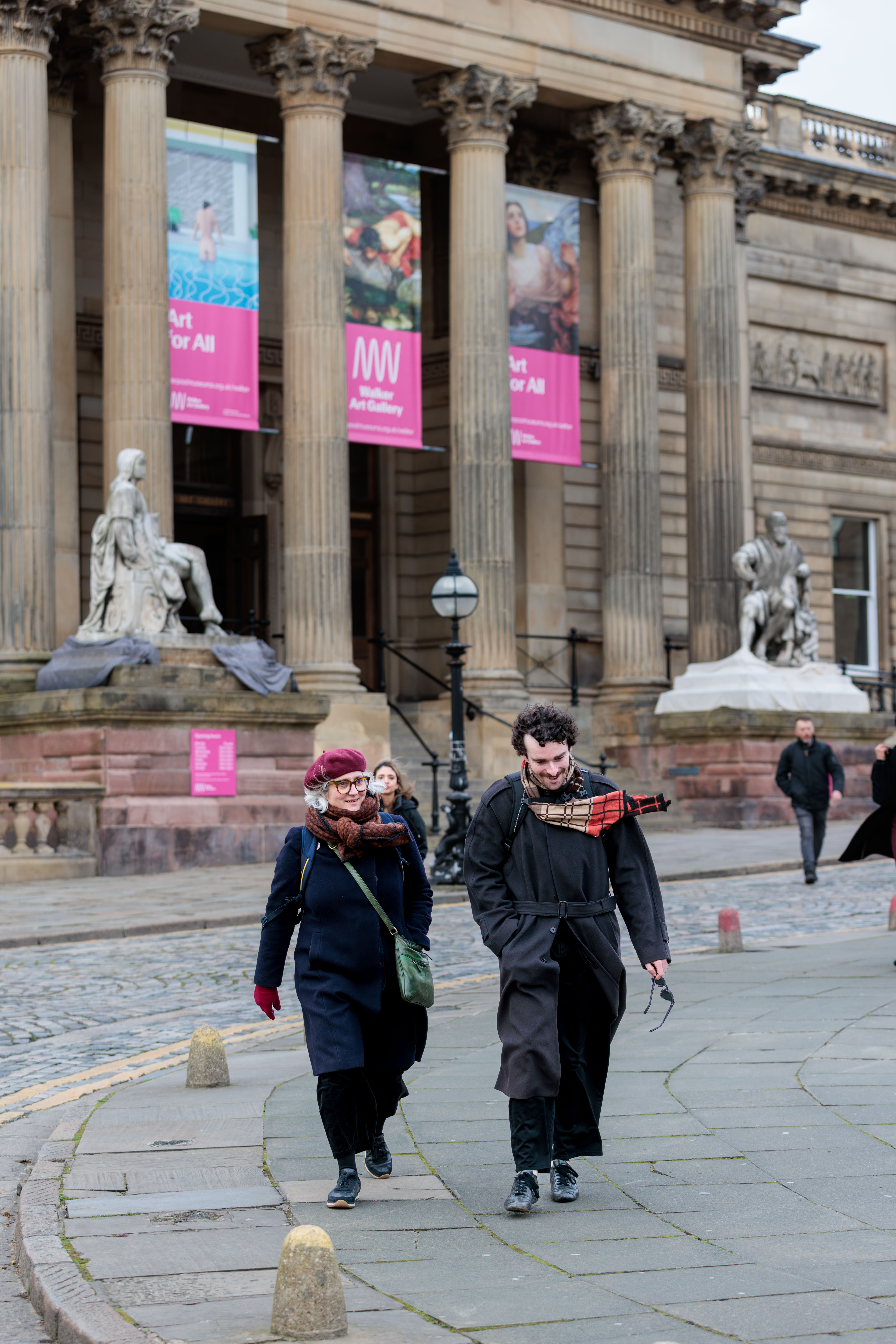 Two people walk outside St George's Hall in Liverpool