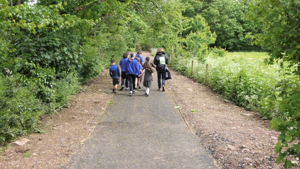a group of school children wearing blue jumpers walking on a footpath
