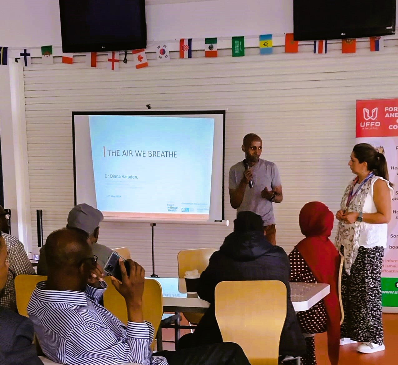 Mohammed stands by a projector screen that says The Air We Breathe
