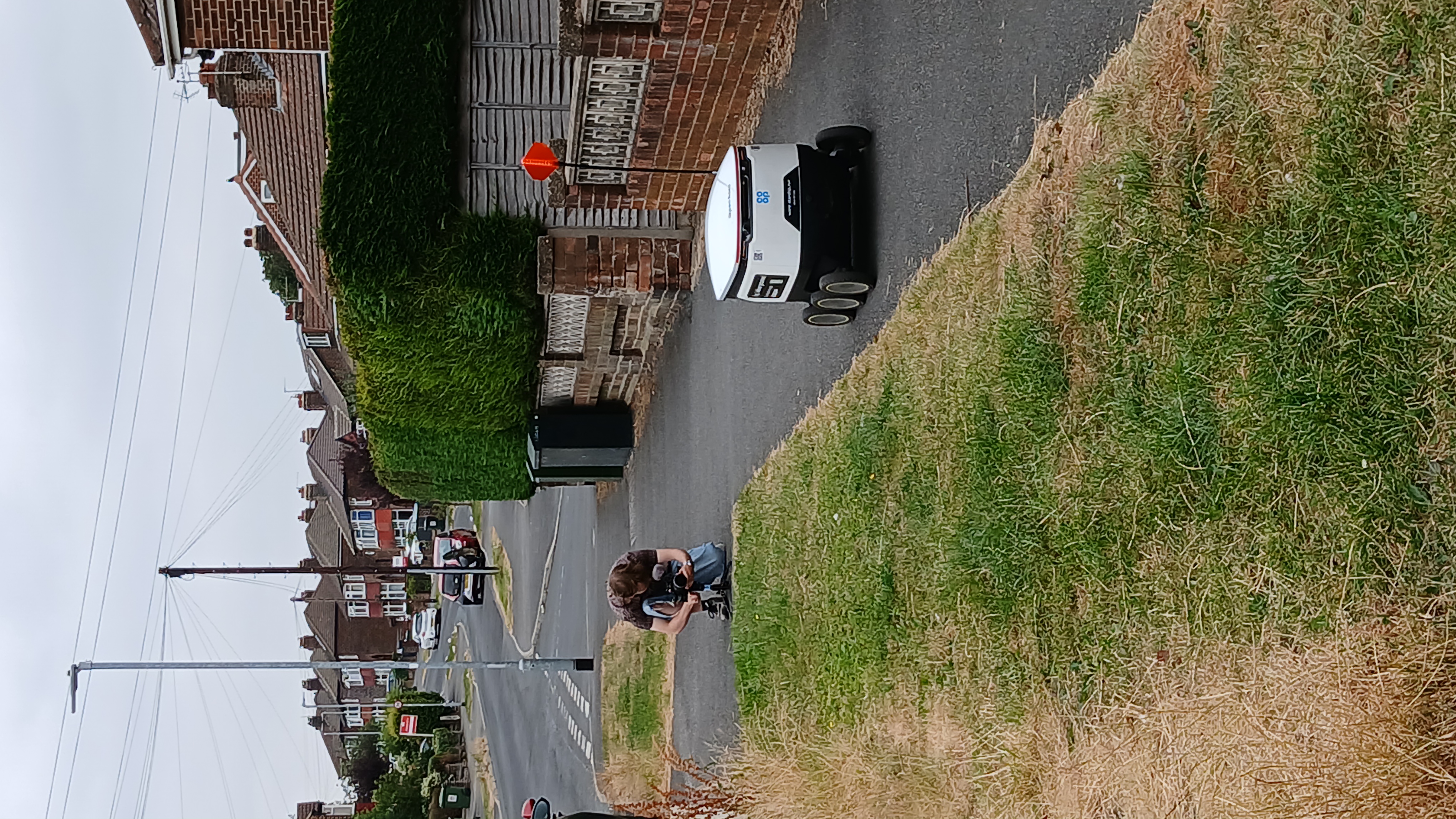 A person films a delivery robot operating on a pavement