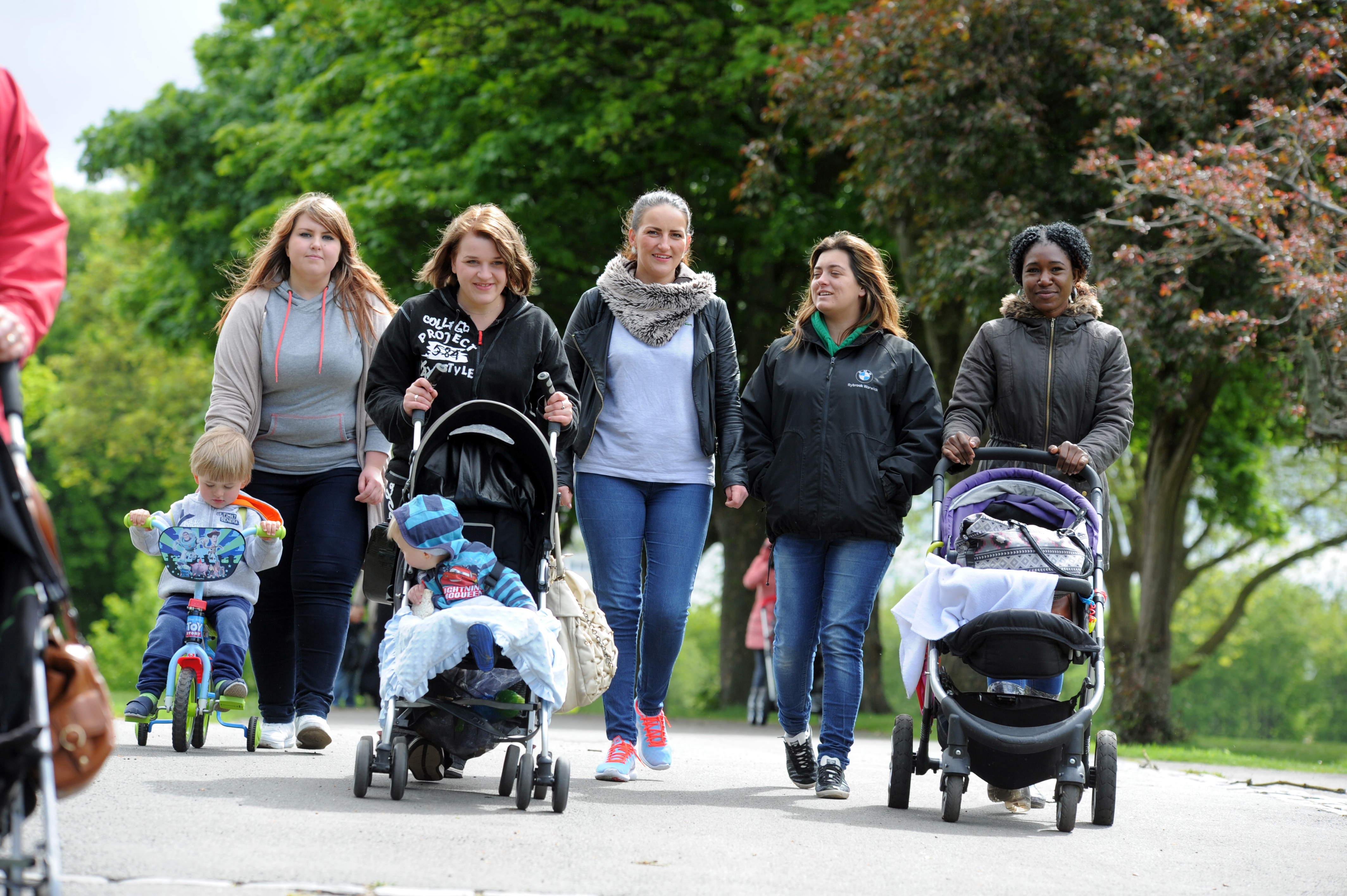 A group of parents walking down the street with children