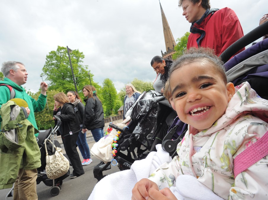 A young child in a pushchair smiles into the camera