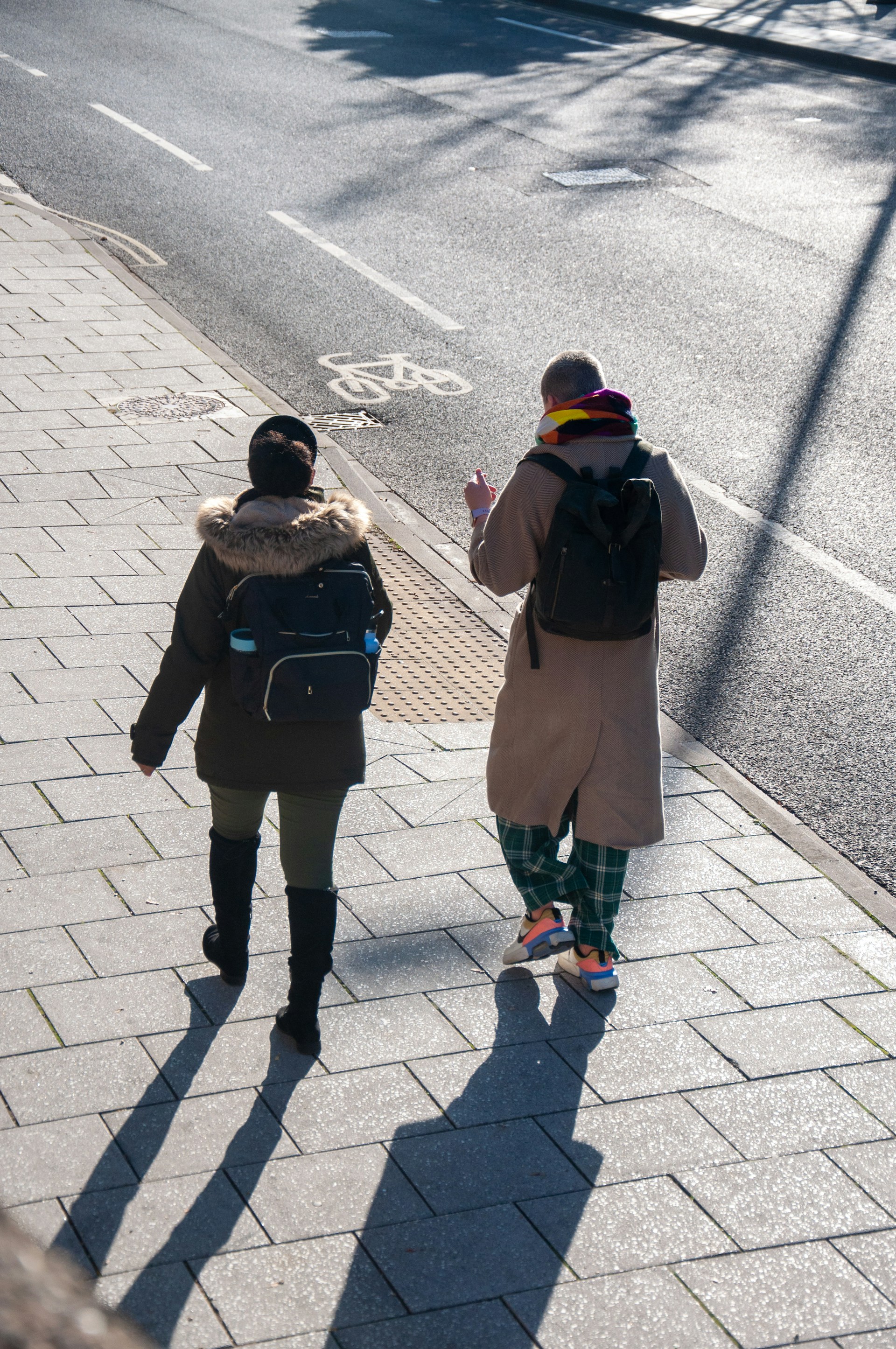 Two people walk down an urban street, chatting.