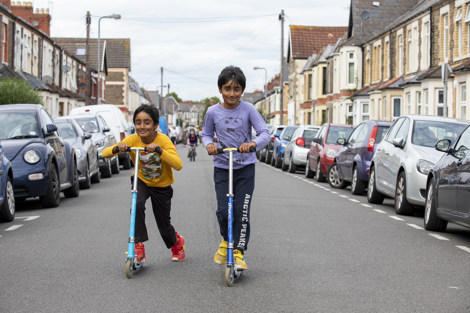 Two children scooting down a street