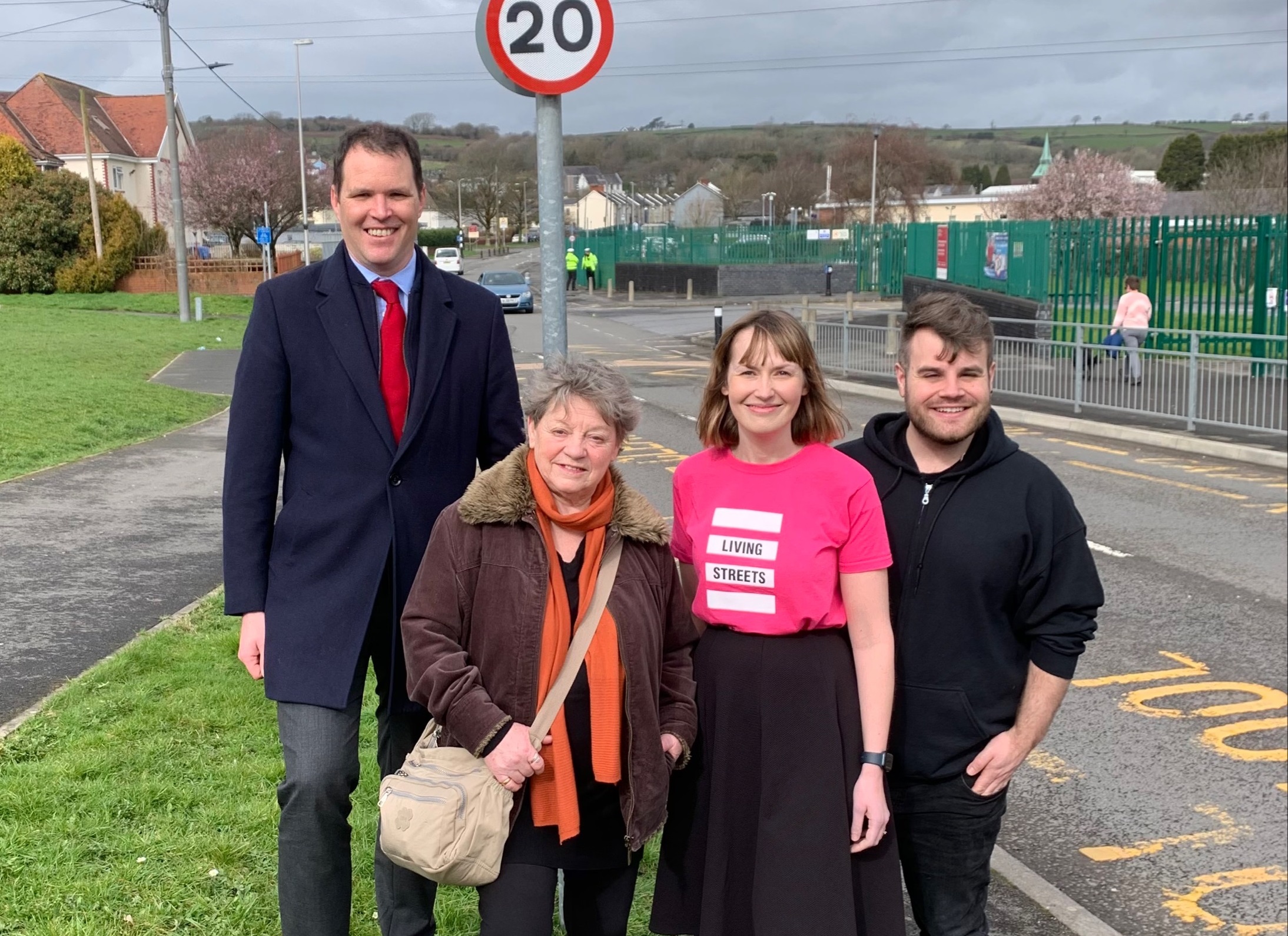 An image of people stood in front of a 20mph sign in Cardiff