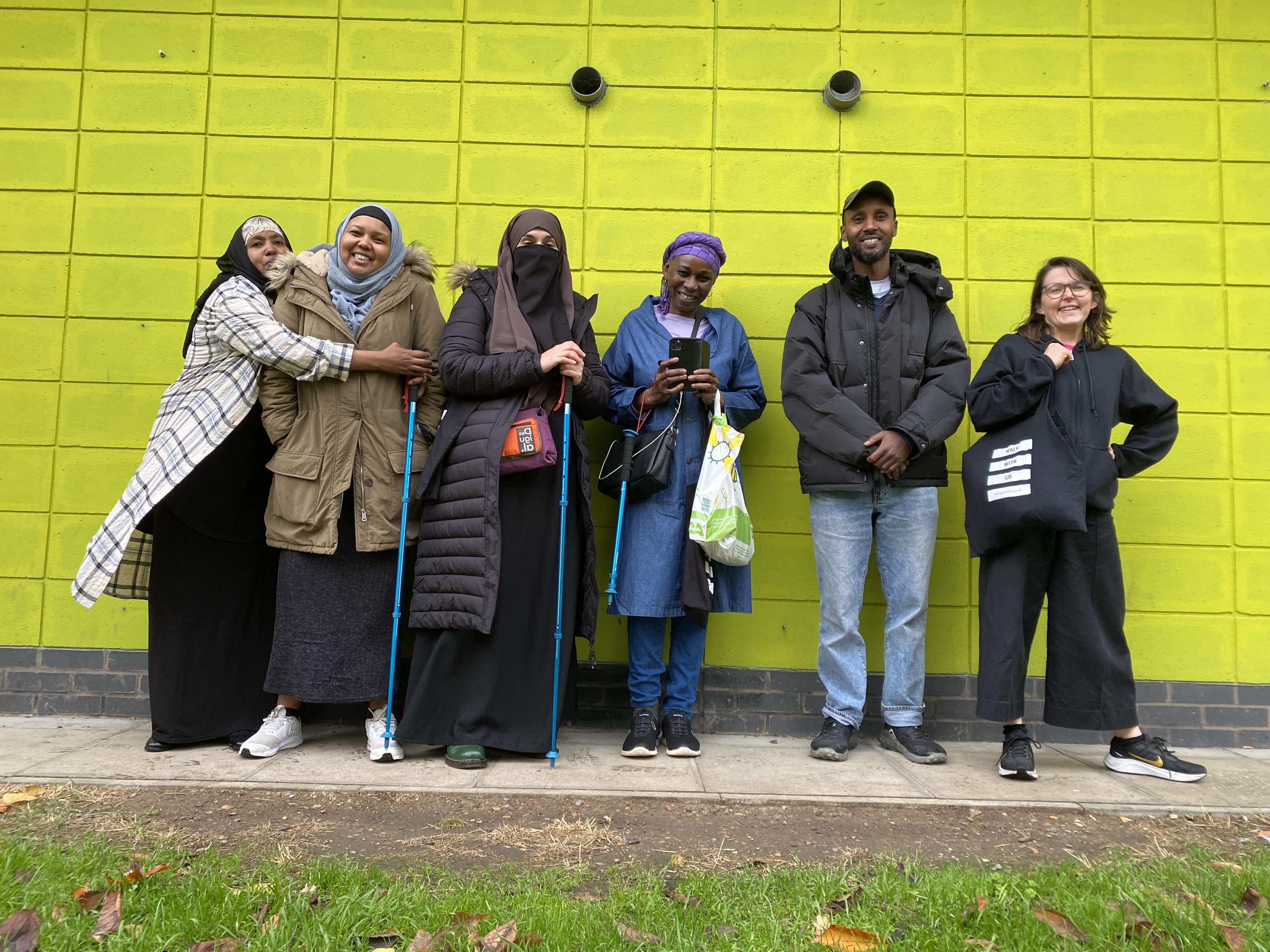 the local group stands in front of a green wall smiling, Amy is with them