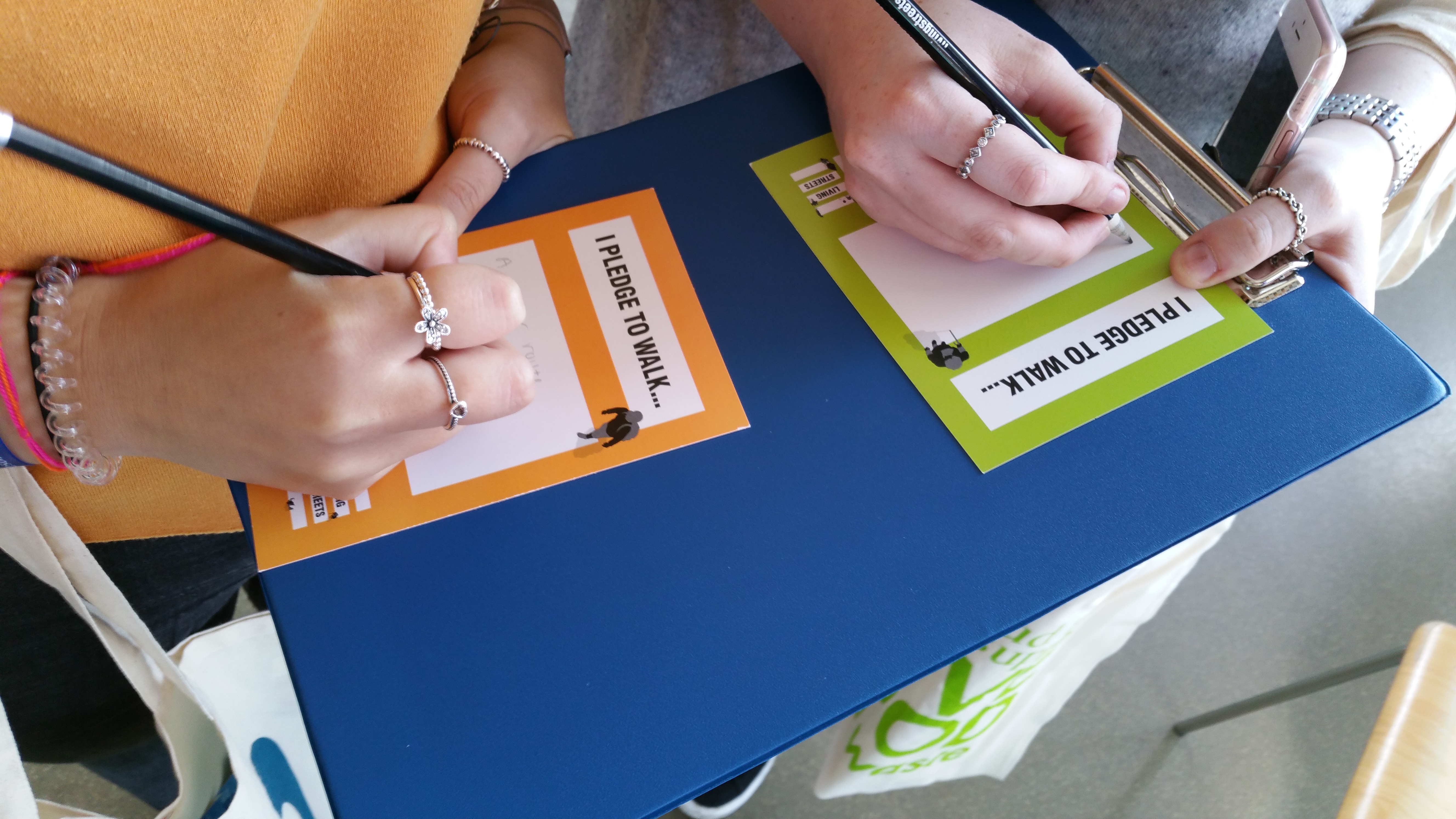 two peoples hands signing pledge cards