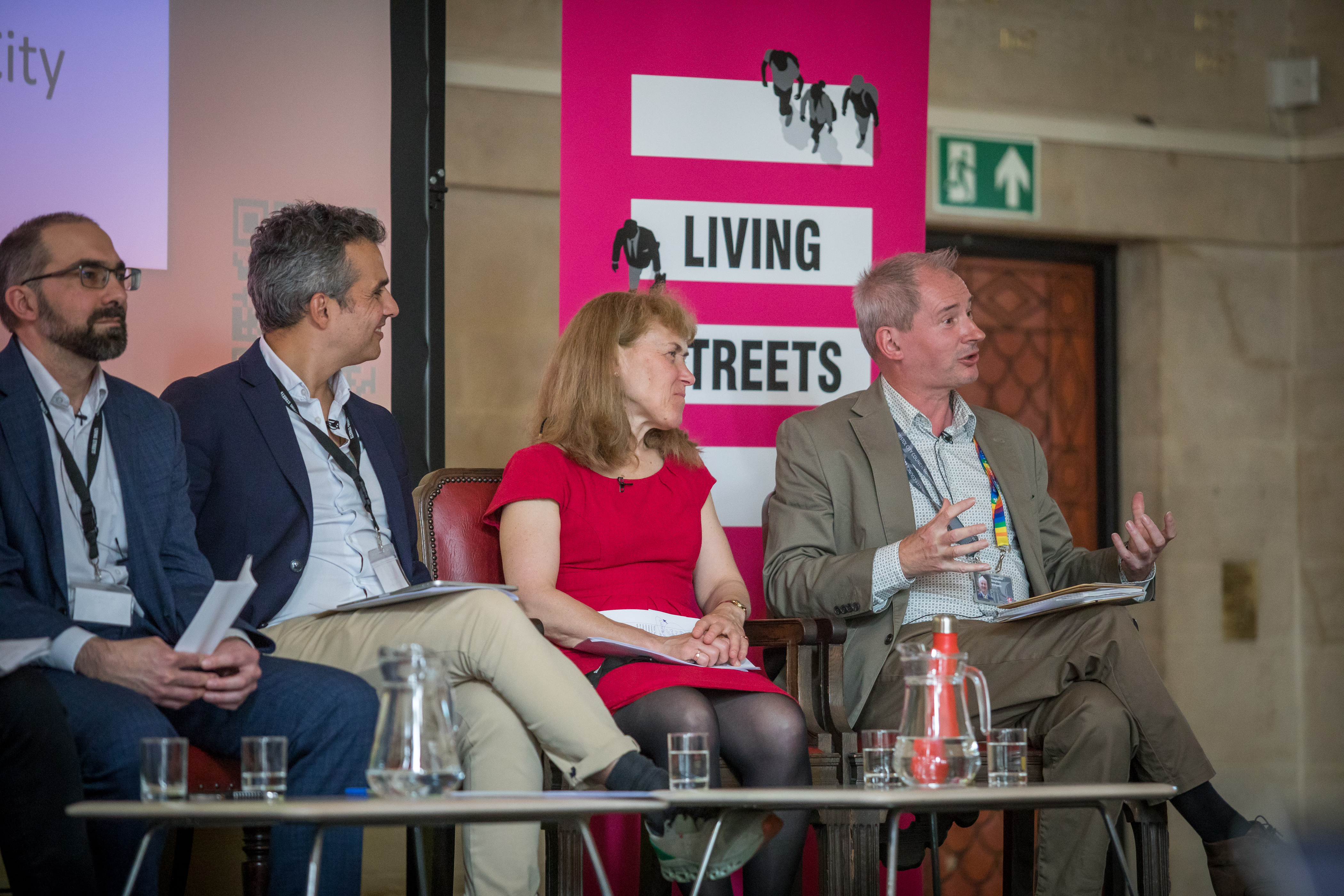 Daniel Godfrey, Andre Neves, Scarlett McNally and Cllr Stephen Williams sit next to each other on-stage at the UK Walking Summit, Cllr Williams is speaking.