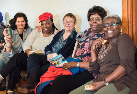 5 women of mixed races and ages smile at the camera