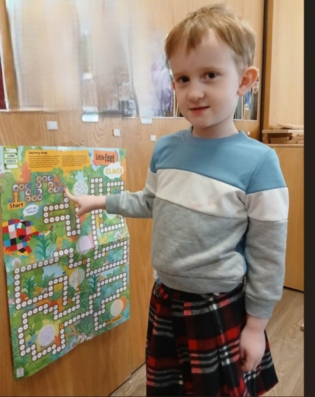 a small child wearing a kilt and pointing at a map in a classroom