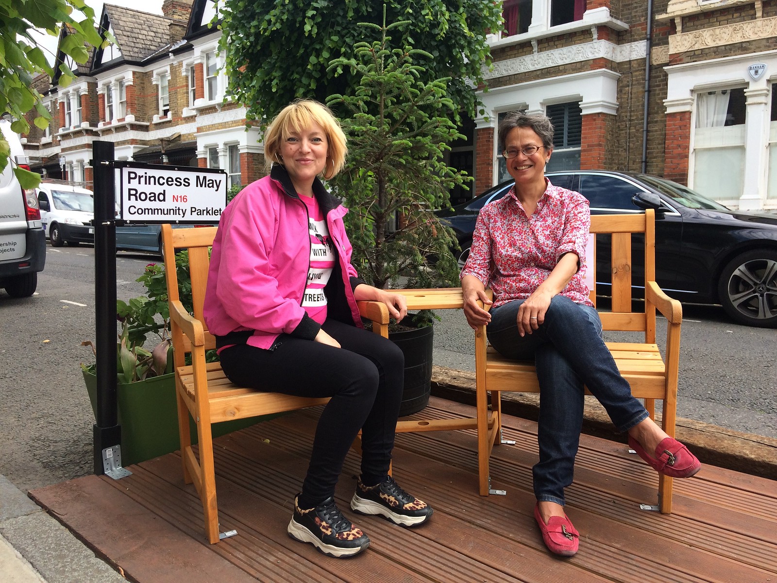 a living streets staff member sits on a bench in a parklet with another woman