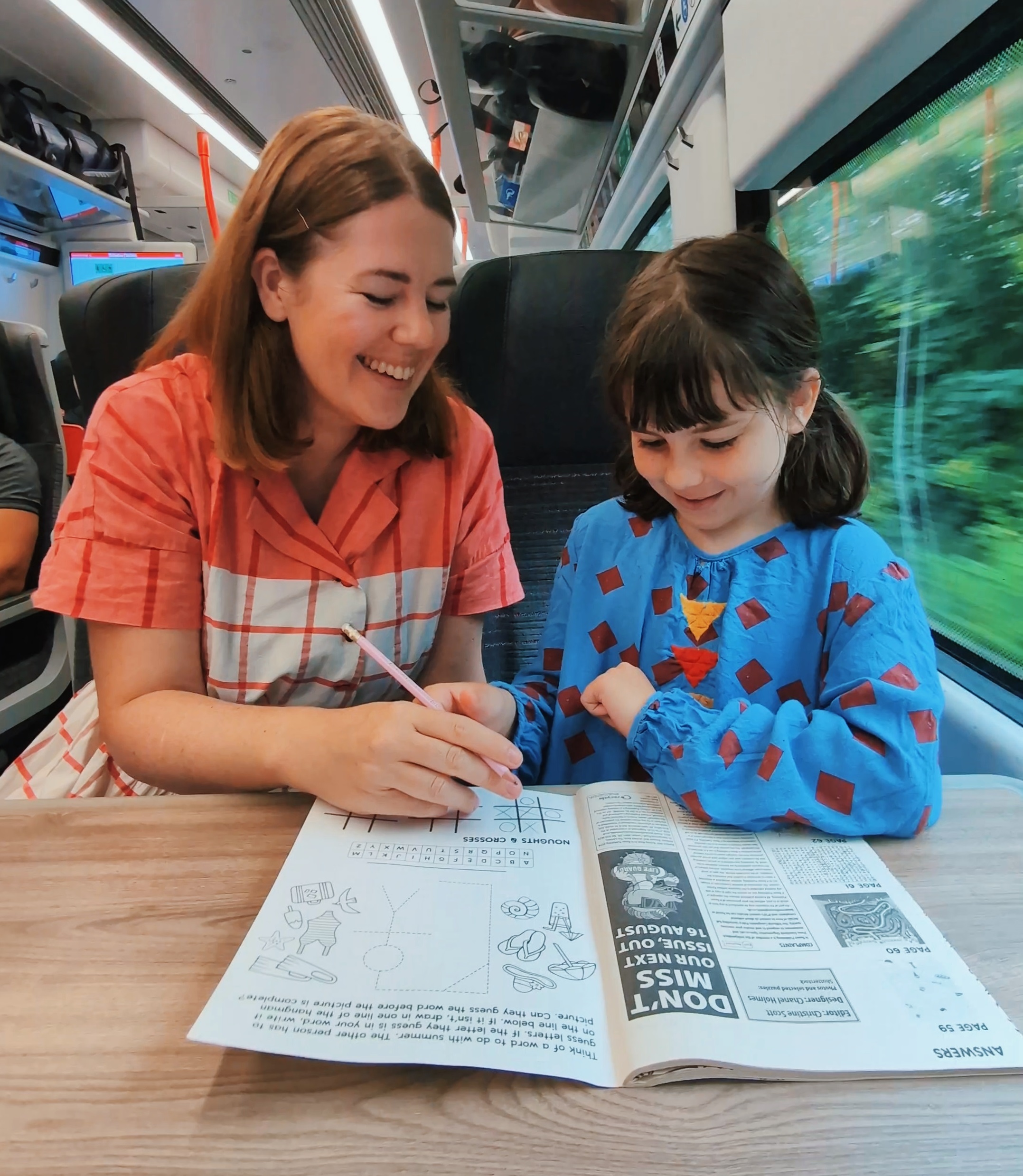 A photograph of a mother and child doing puzzles together on a train journey