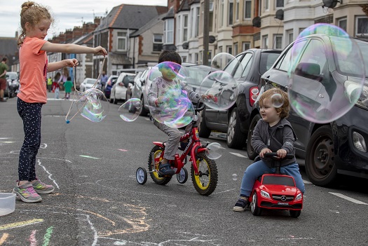 children play in street with bubbles and bikes