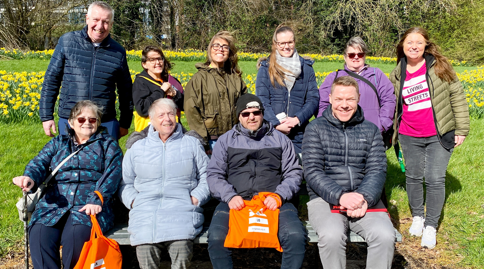 a group of people pose on a park bench, including a living streets staff member