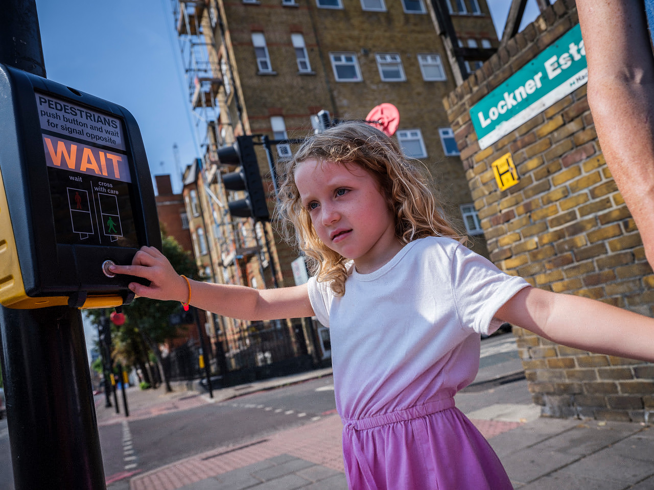 A young girl pressing the button at a controlled crossing