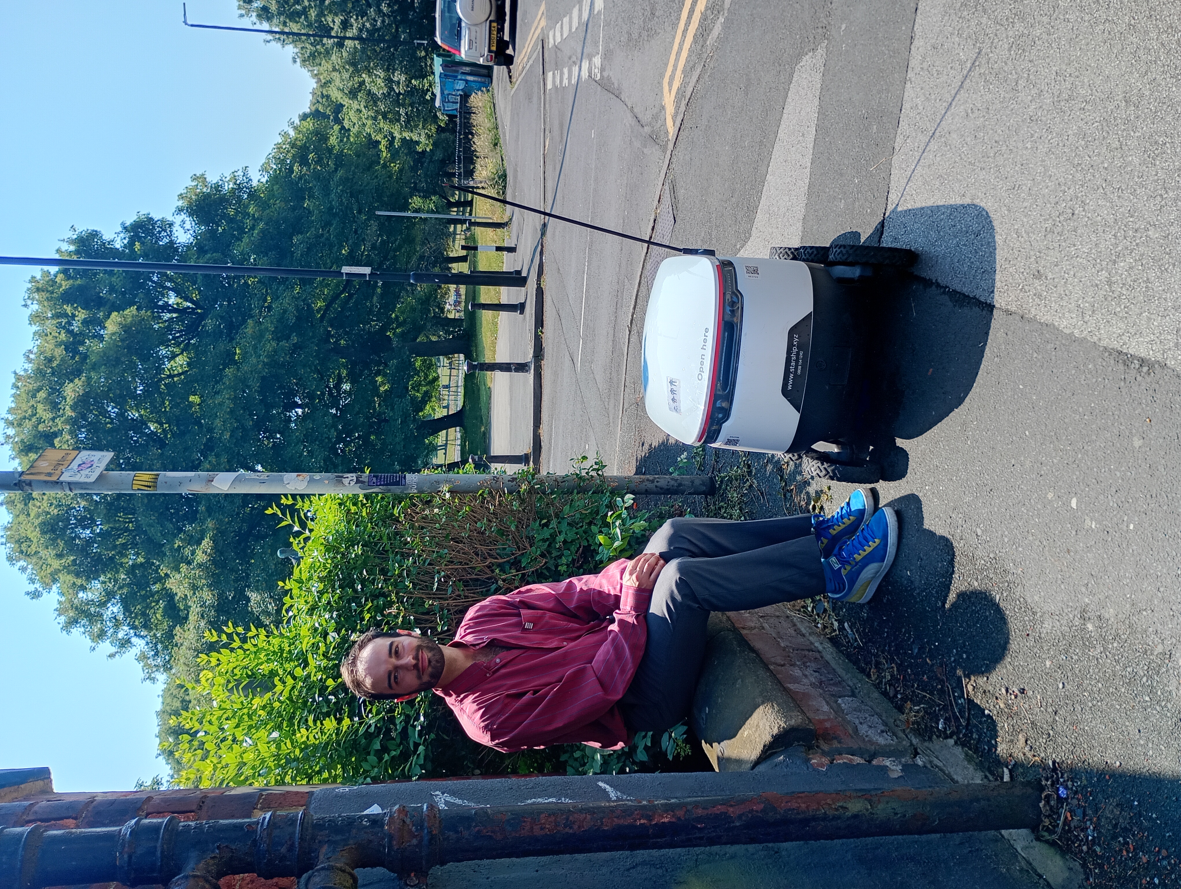 Zak Viney poses with a delivery robot in Leeds