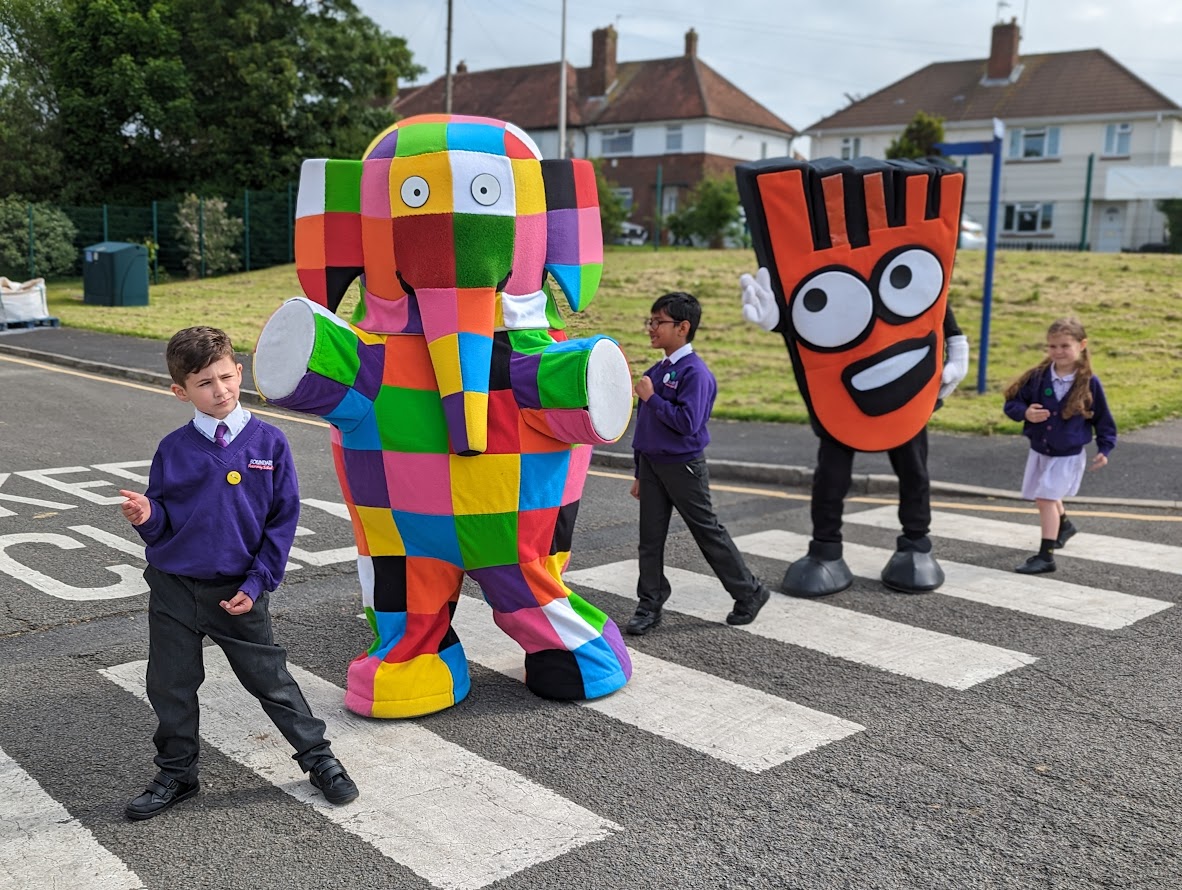 Pupils from Boundary Primary School in Blackpool are stood on a zebra crossing with Elmer the Patchwork elephant