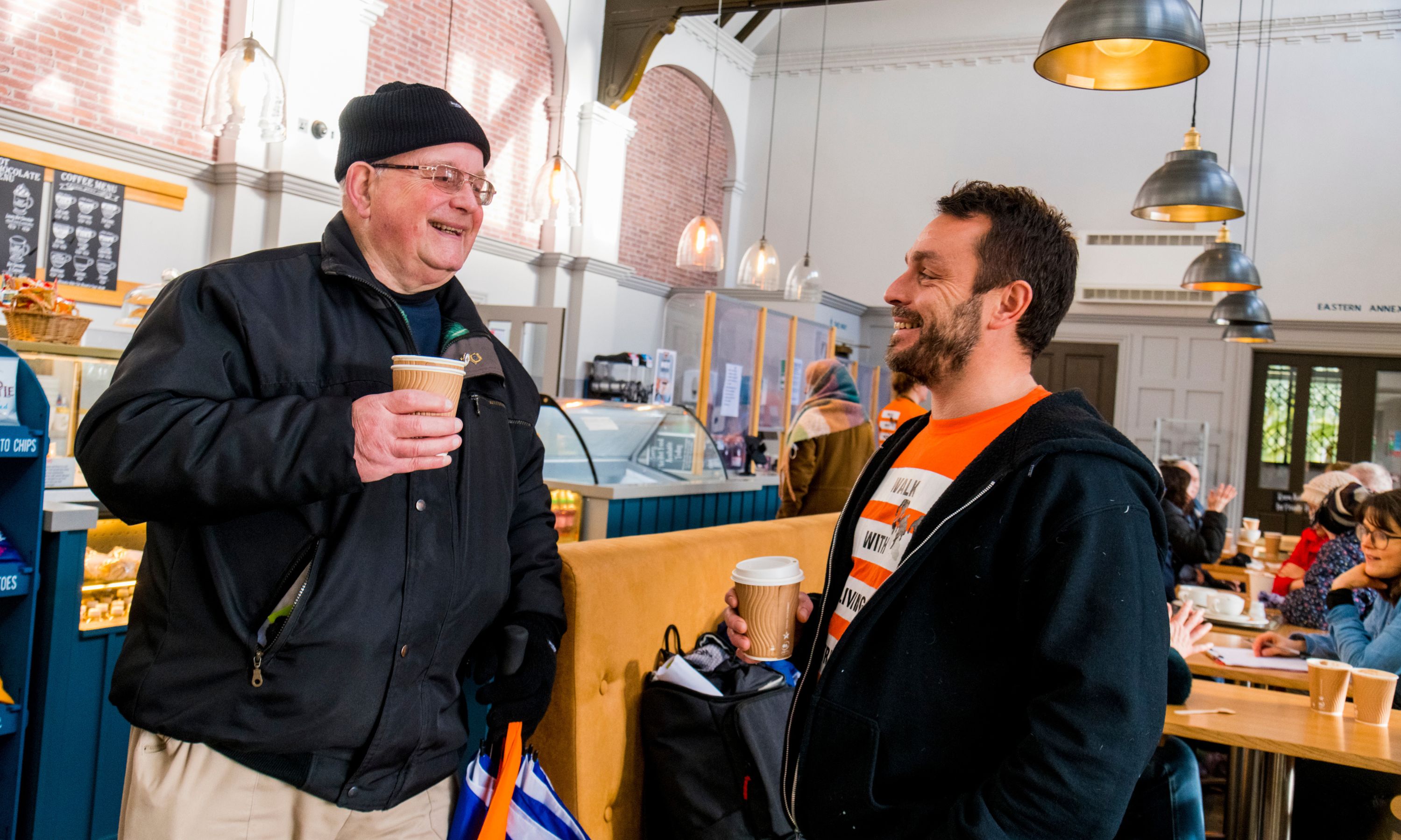 two men laughing and drinking tea in a cafe