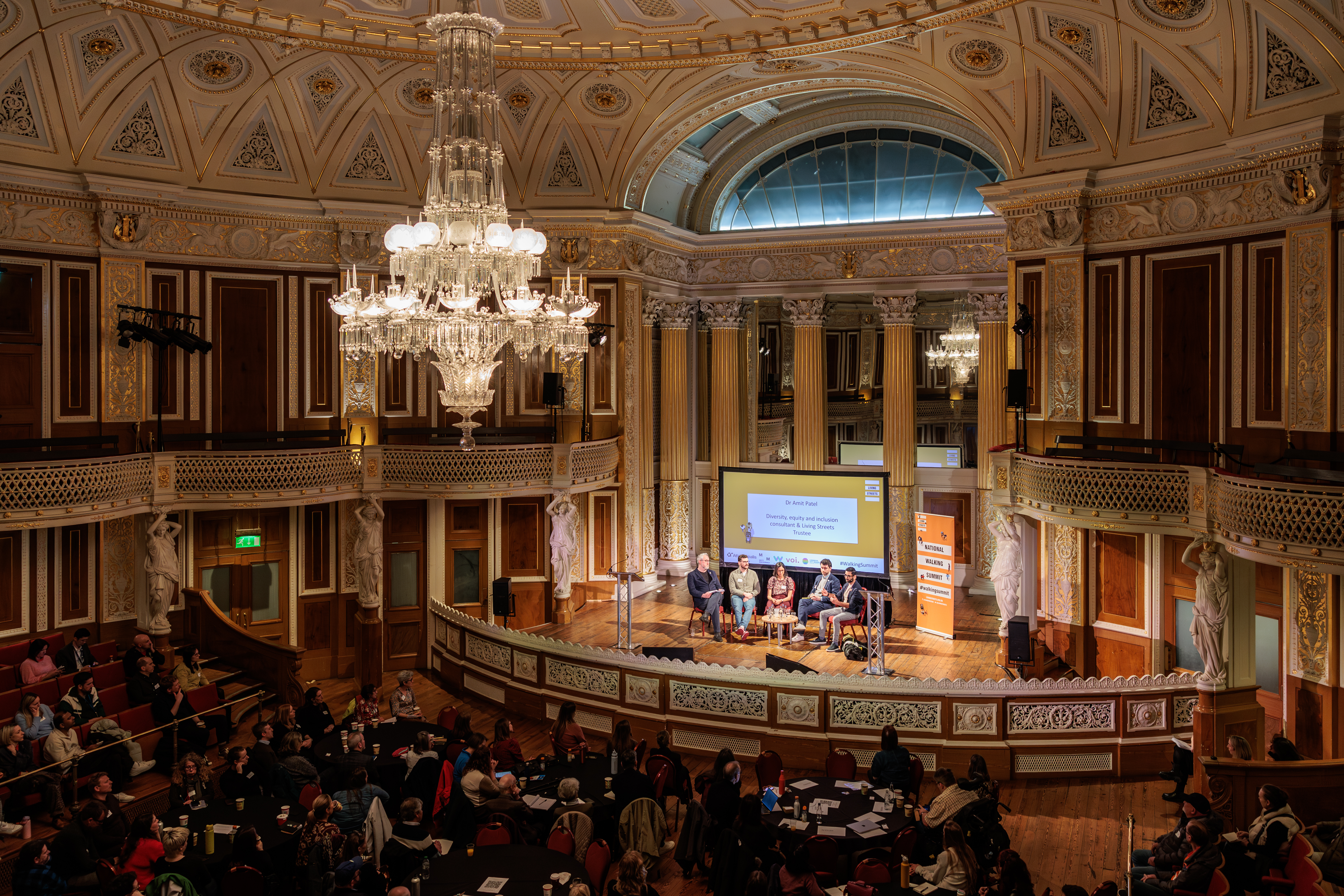 A shot of a panel of five people speaking to a large audience in St George's Hall, Liverpool