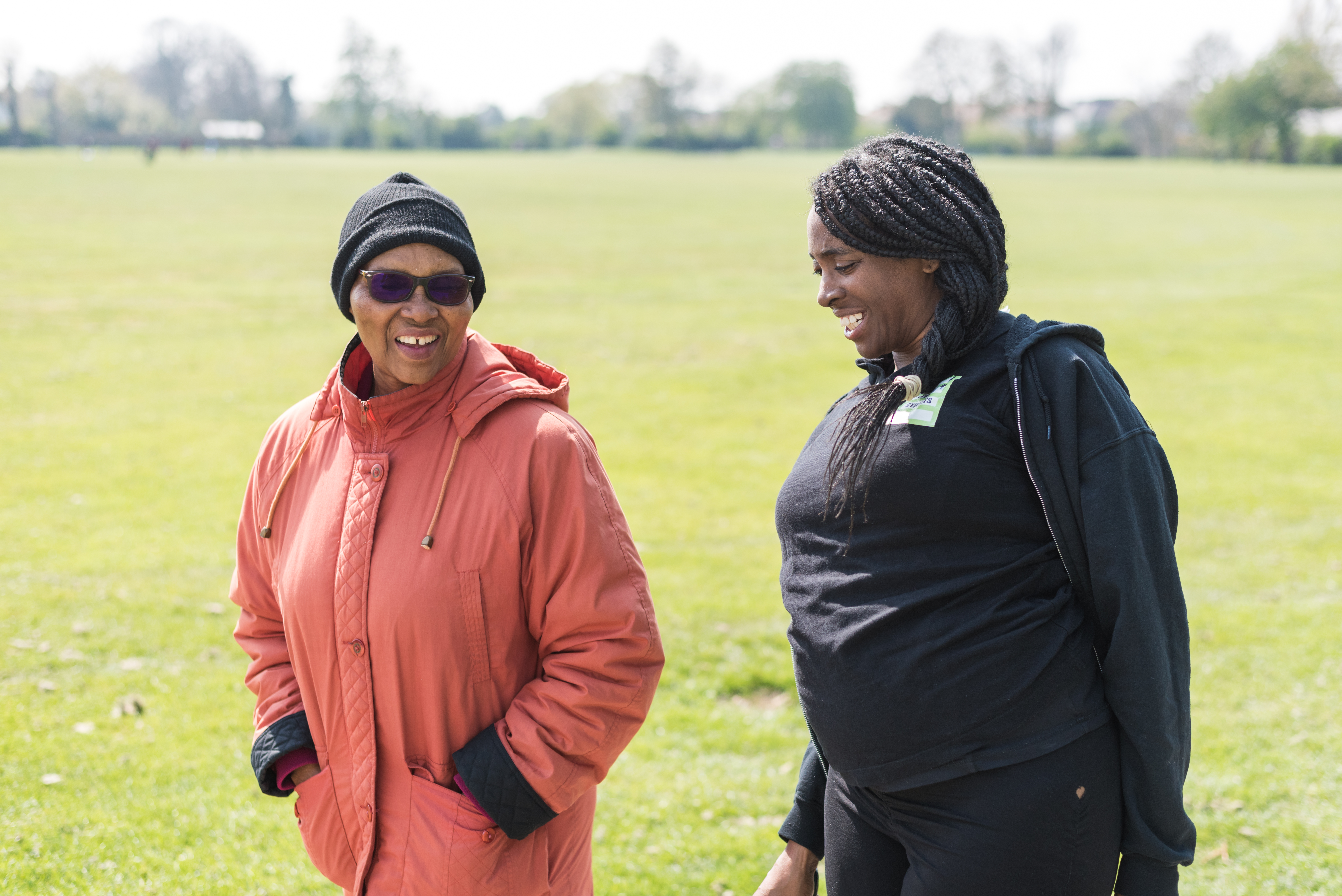 two black women walking in a park smiling, one is a Living Streets staff member