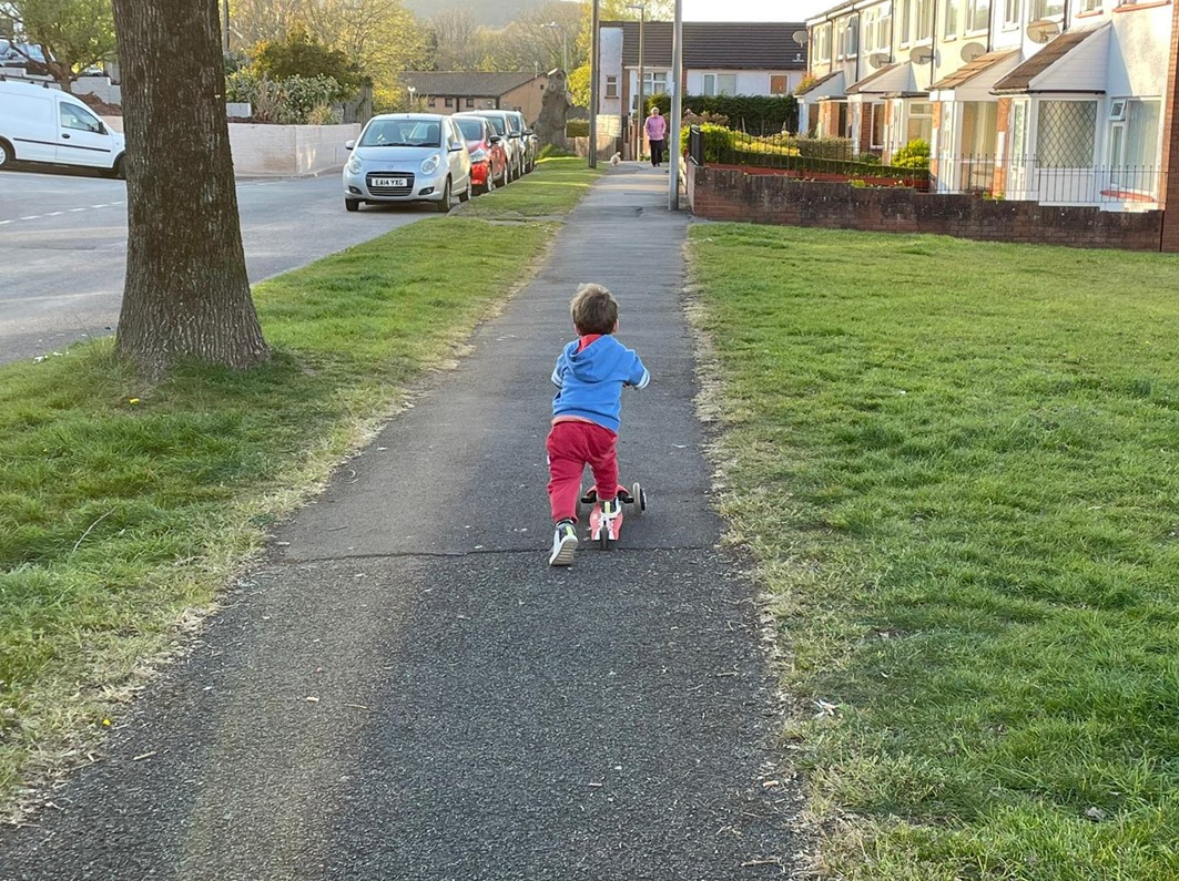 A child rides a scooter on a residential street