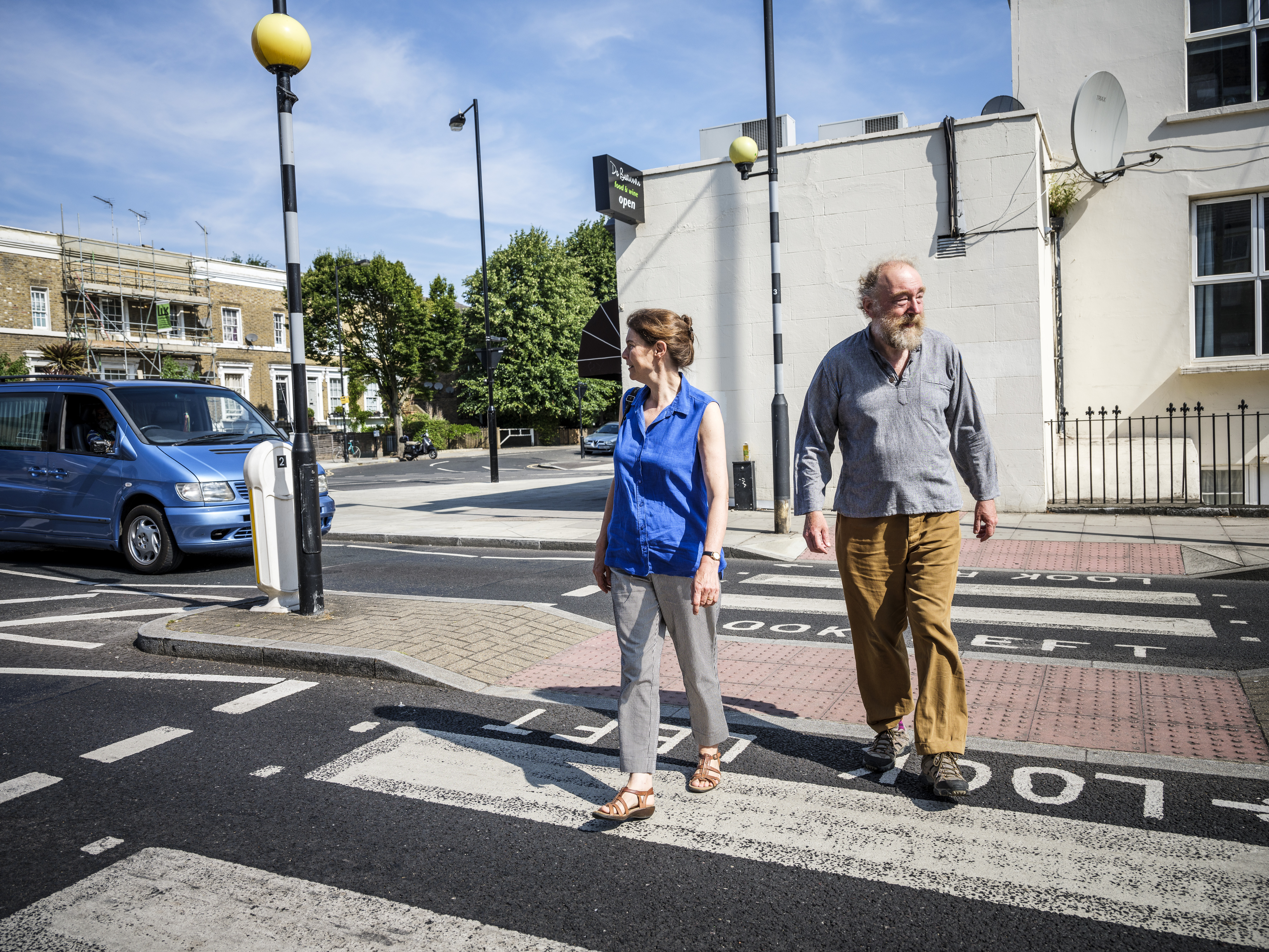 an older couple cross a zebra crossing