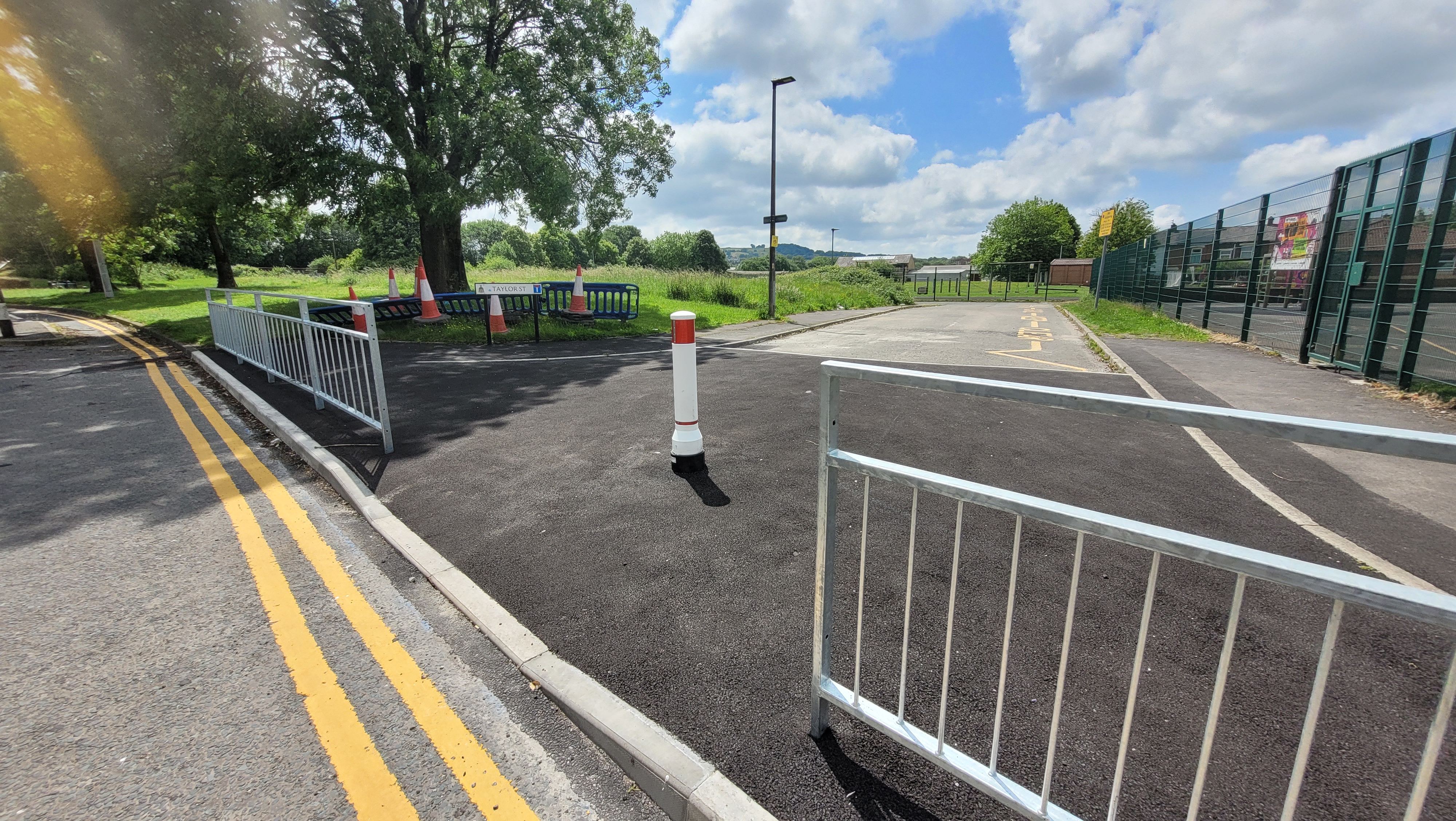 an image of a junction with railings, road markings and a dropped kerb