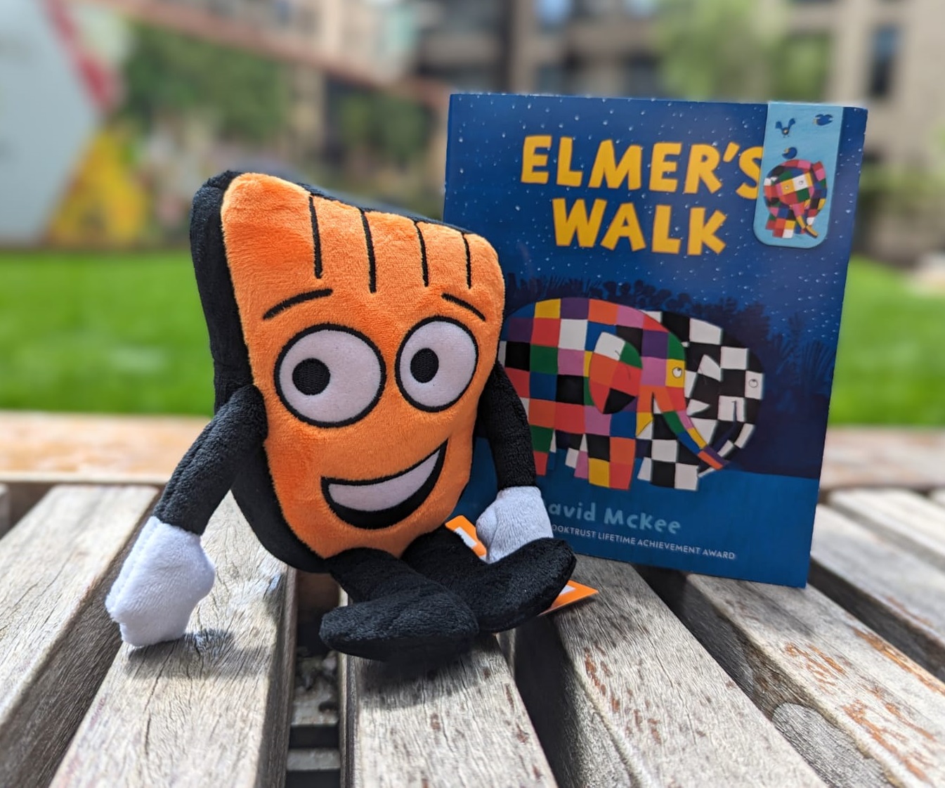 A Strider plush toy sitting next to the Elmer's Walk book on a table.