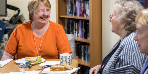 three older women sit around a table talking and laughing