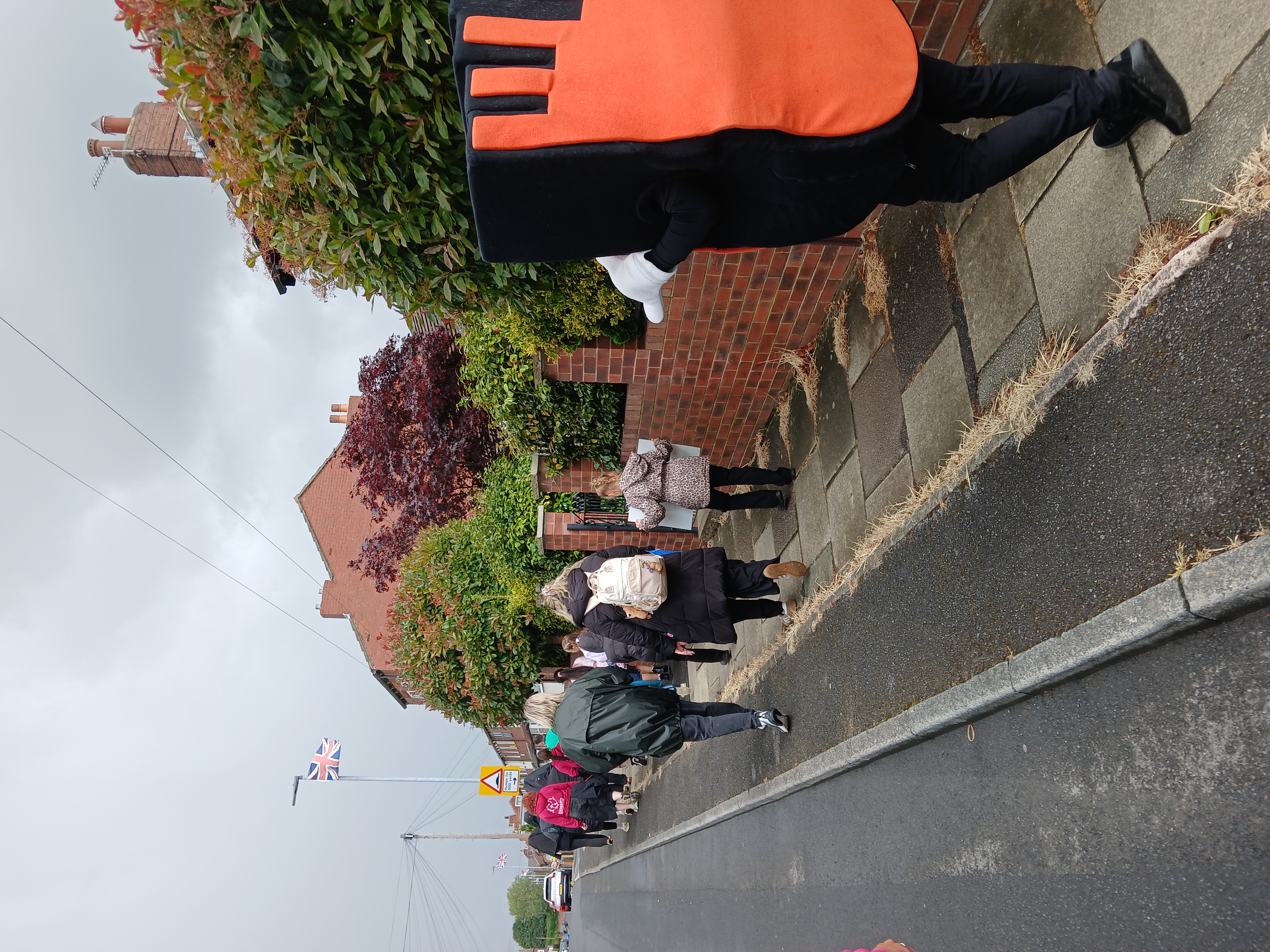 Strider, the Living Streets mascot walks with schoolchildren on a residential street