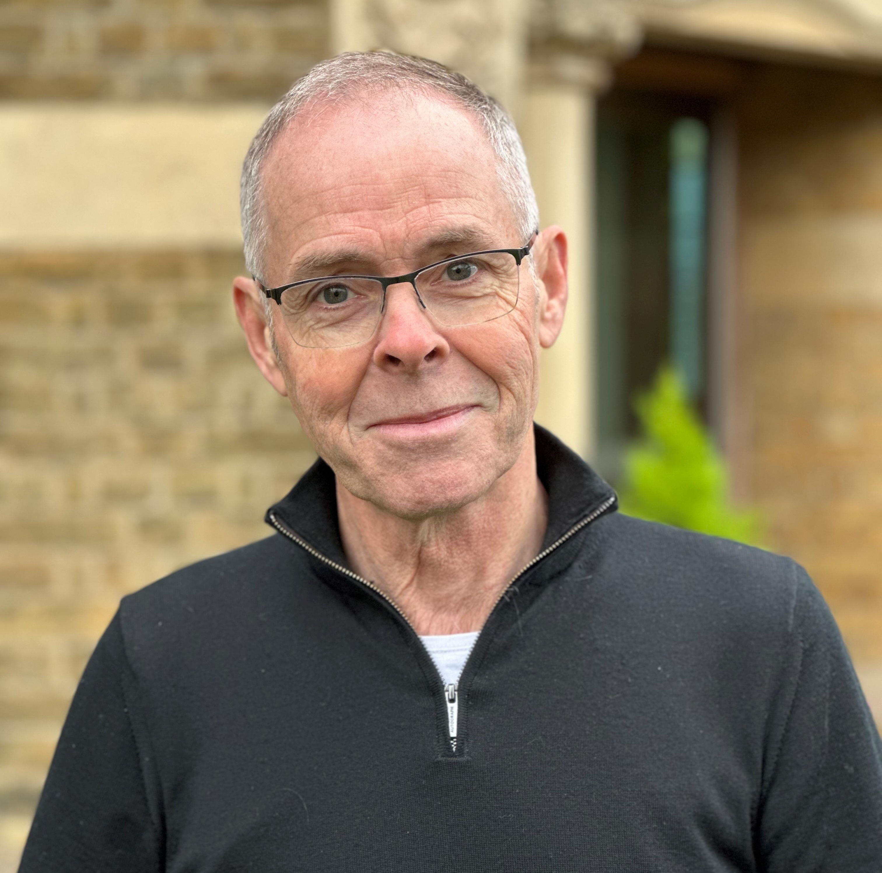 A headshot of John Dales smiling into the camera.