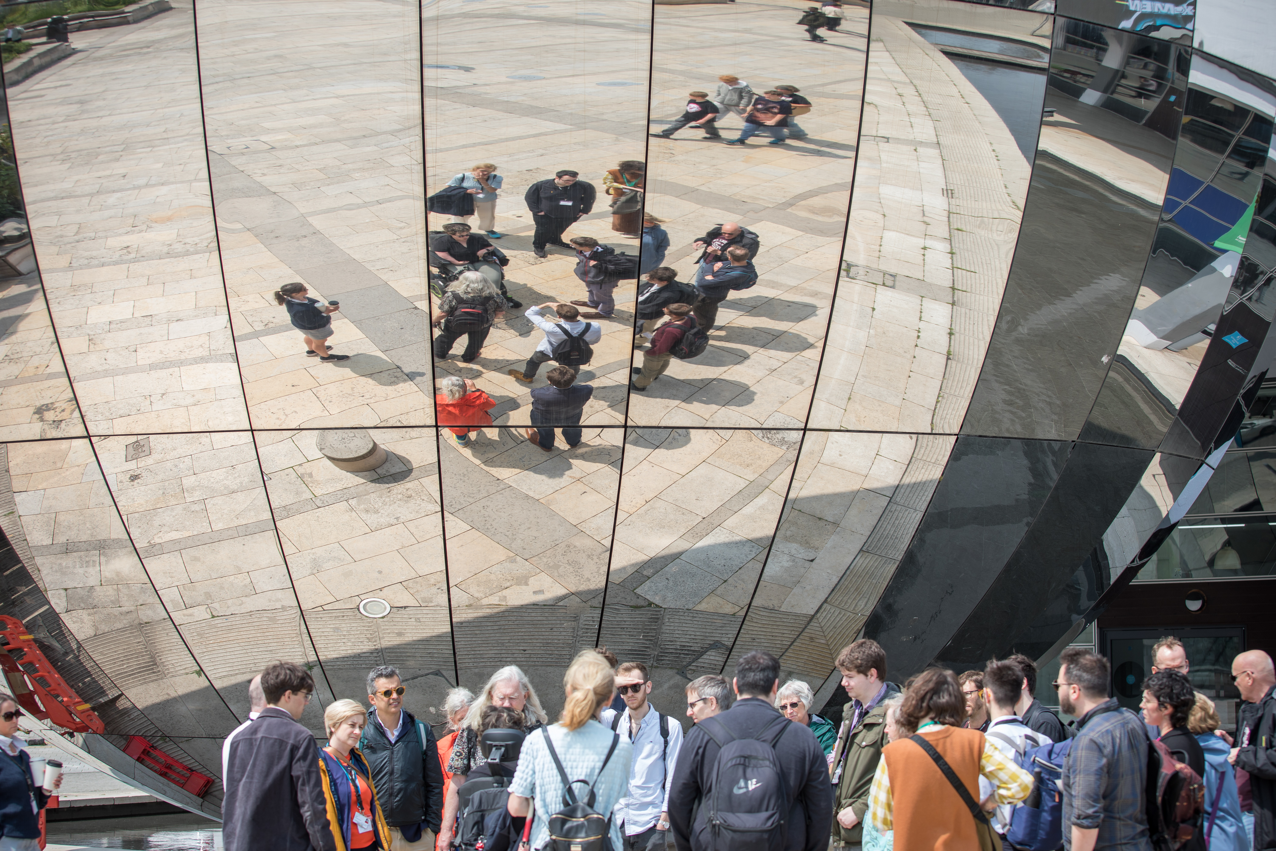 People walking and wheeling enjoy a tour in Bristol, they stand by a reflective dome