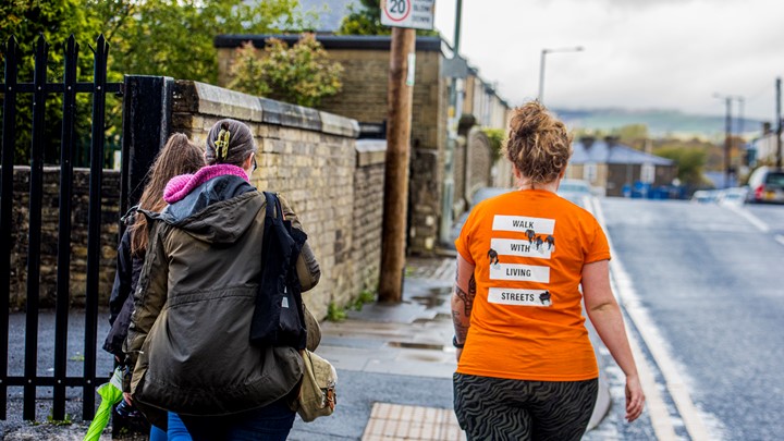 charli walking away from camera in her living streets tshirt that says walk with living streets