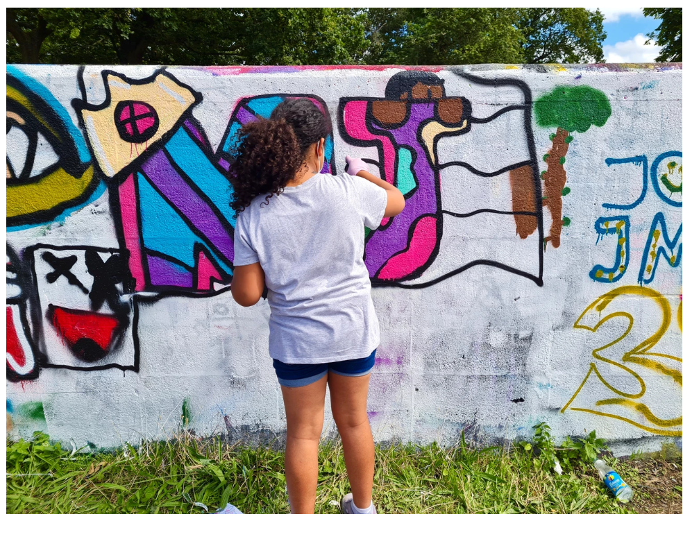 A young person doing street art