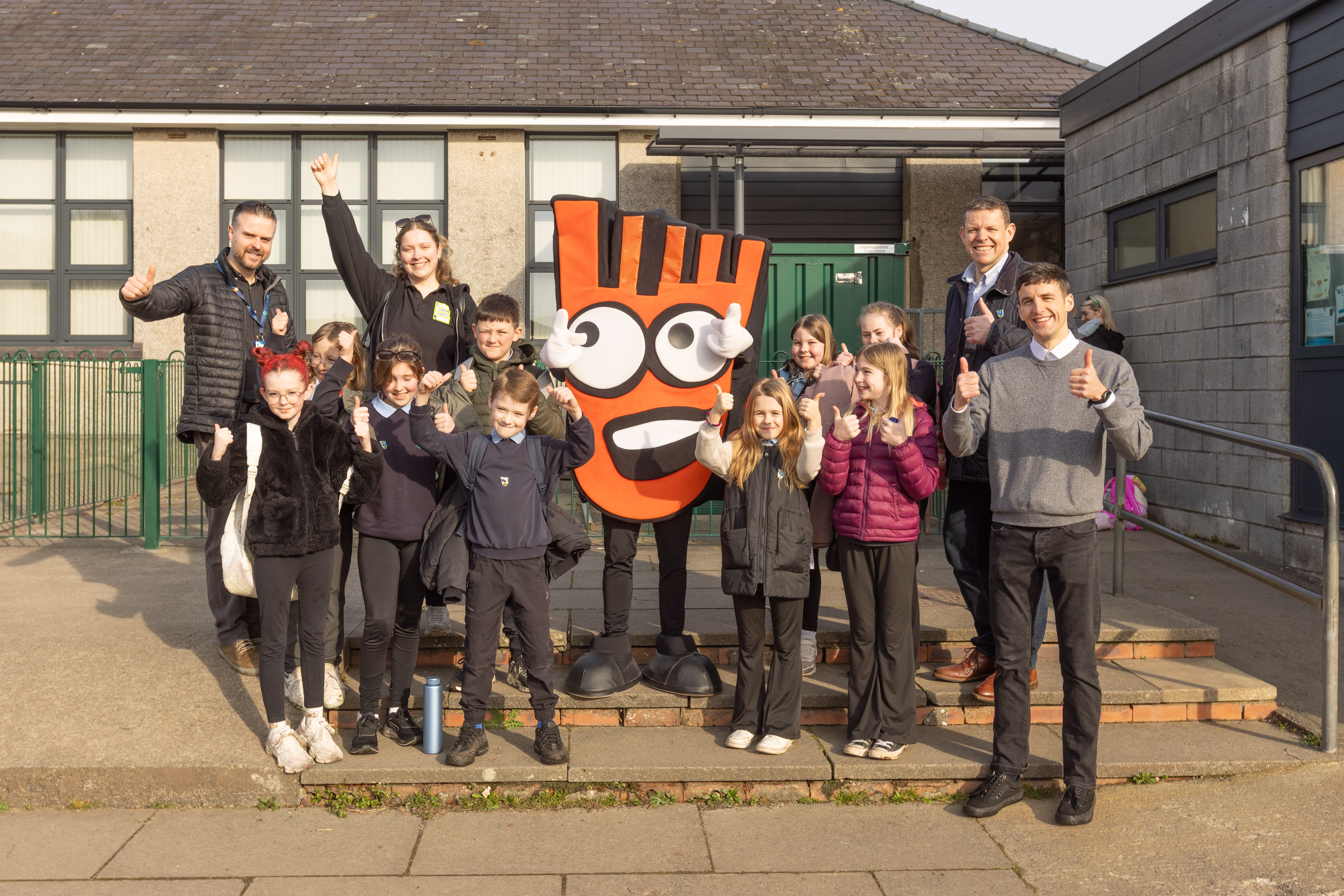 A group of school pupils and adults stand with teachers, Living Streets staff, Rhun ap Iorwerth and Strider