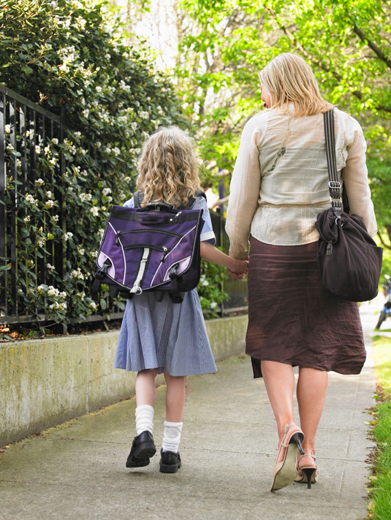 A woman walking with a young school girl