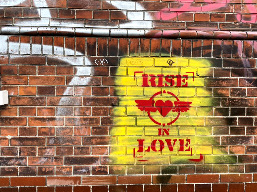 A brick wall with 'Rise in love' graffiti on it