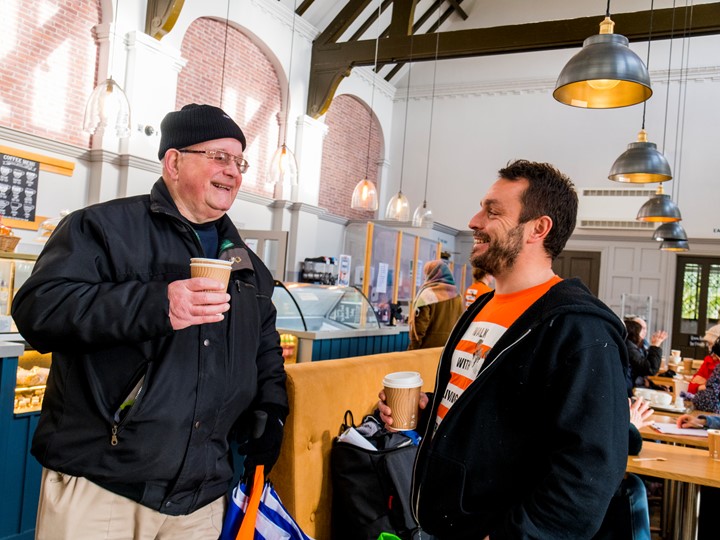 2 men laughing in a coffee shop, one is a living streets staff member