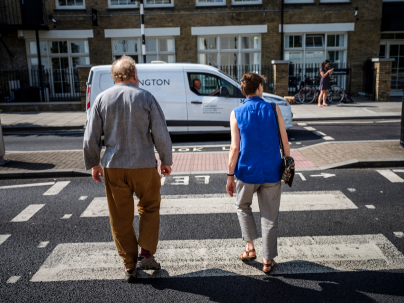 two older people cross a zebra crossing