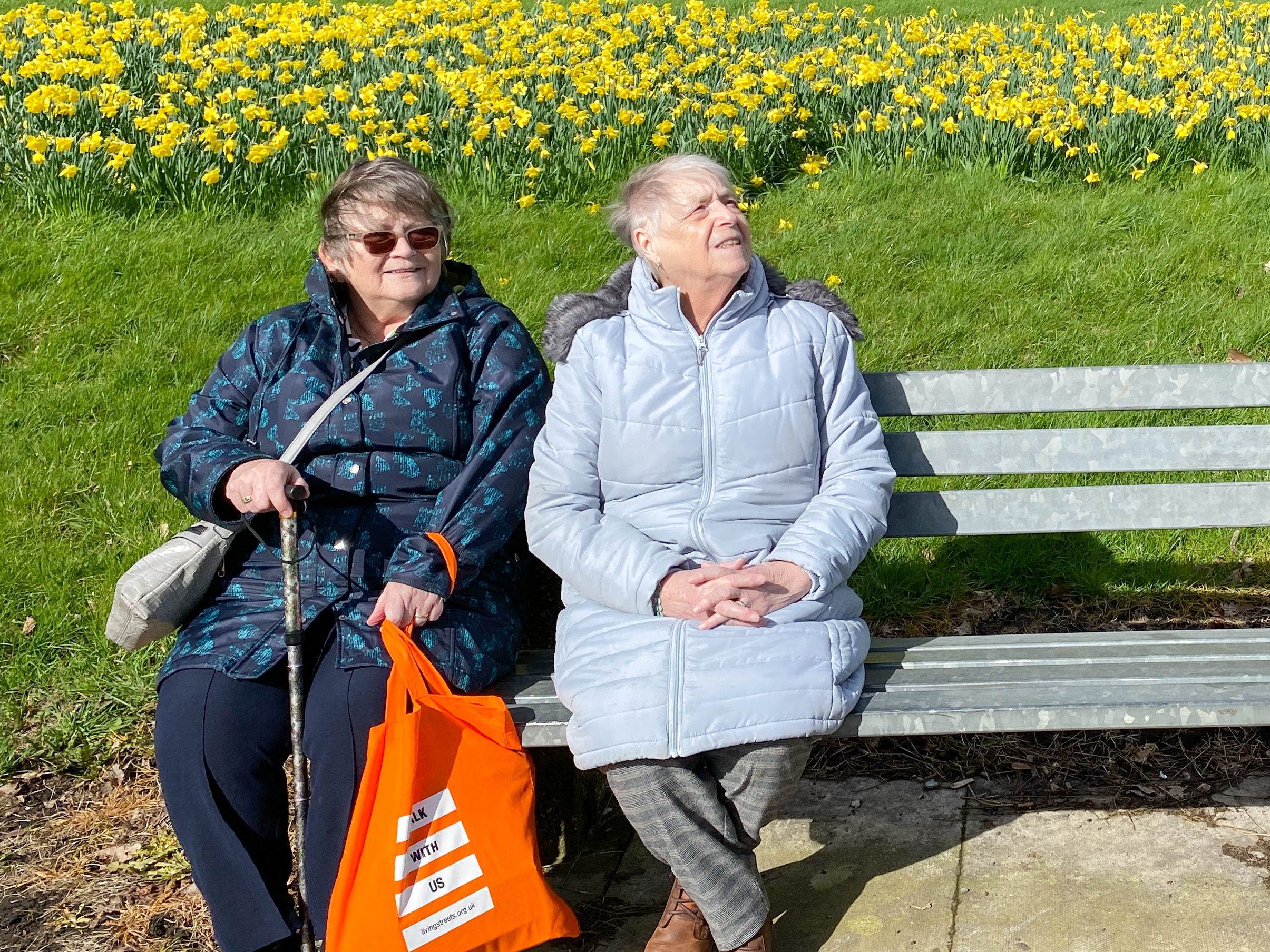 two older women sit on a park bench