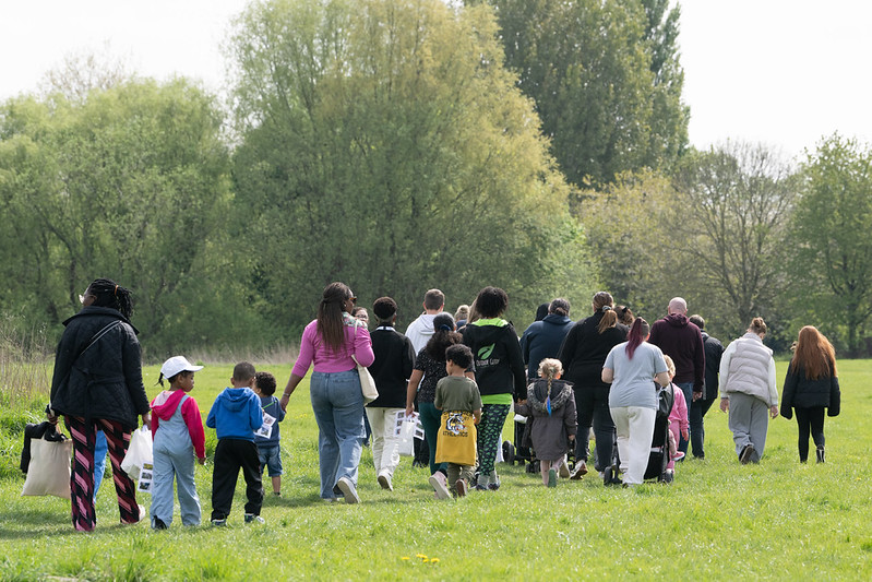 an image of a large group of children and adults walking through a field