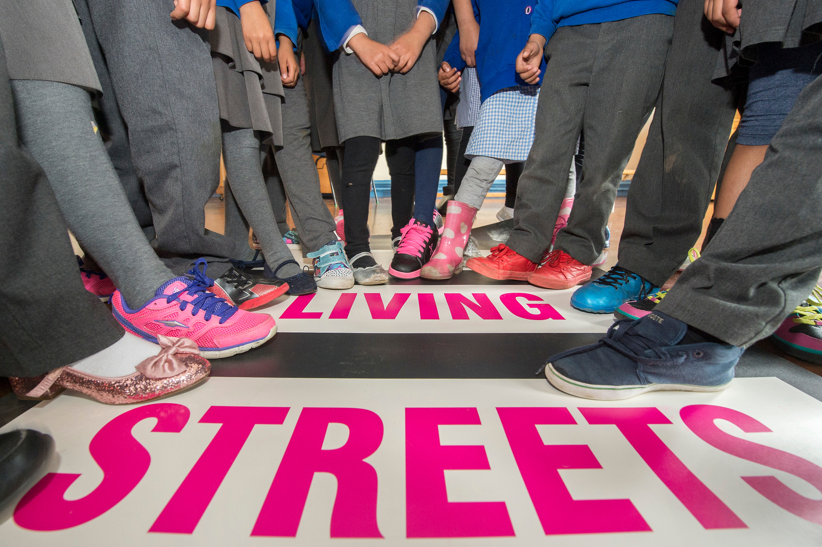 Primary school children pointing shoes to Living Streets logo