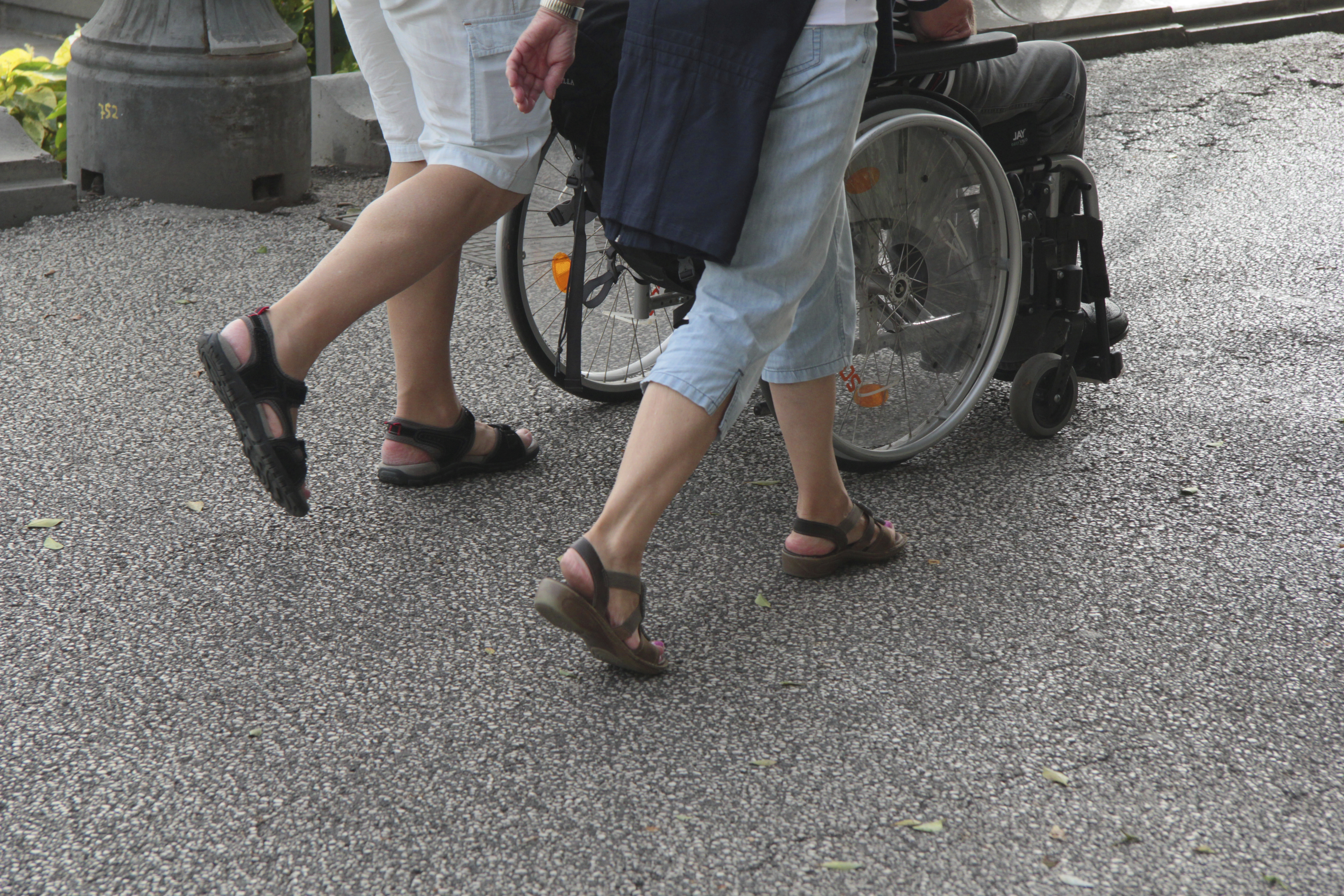 two people walking behind a wheelchair